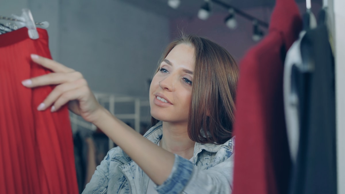 Woman browsing a neatly arranged clothing rack in a boutique.
