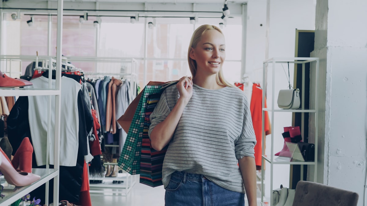 Happy woman walking through a clothing store with shopping bags.