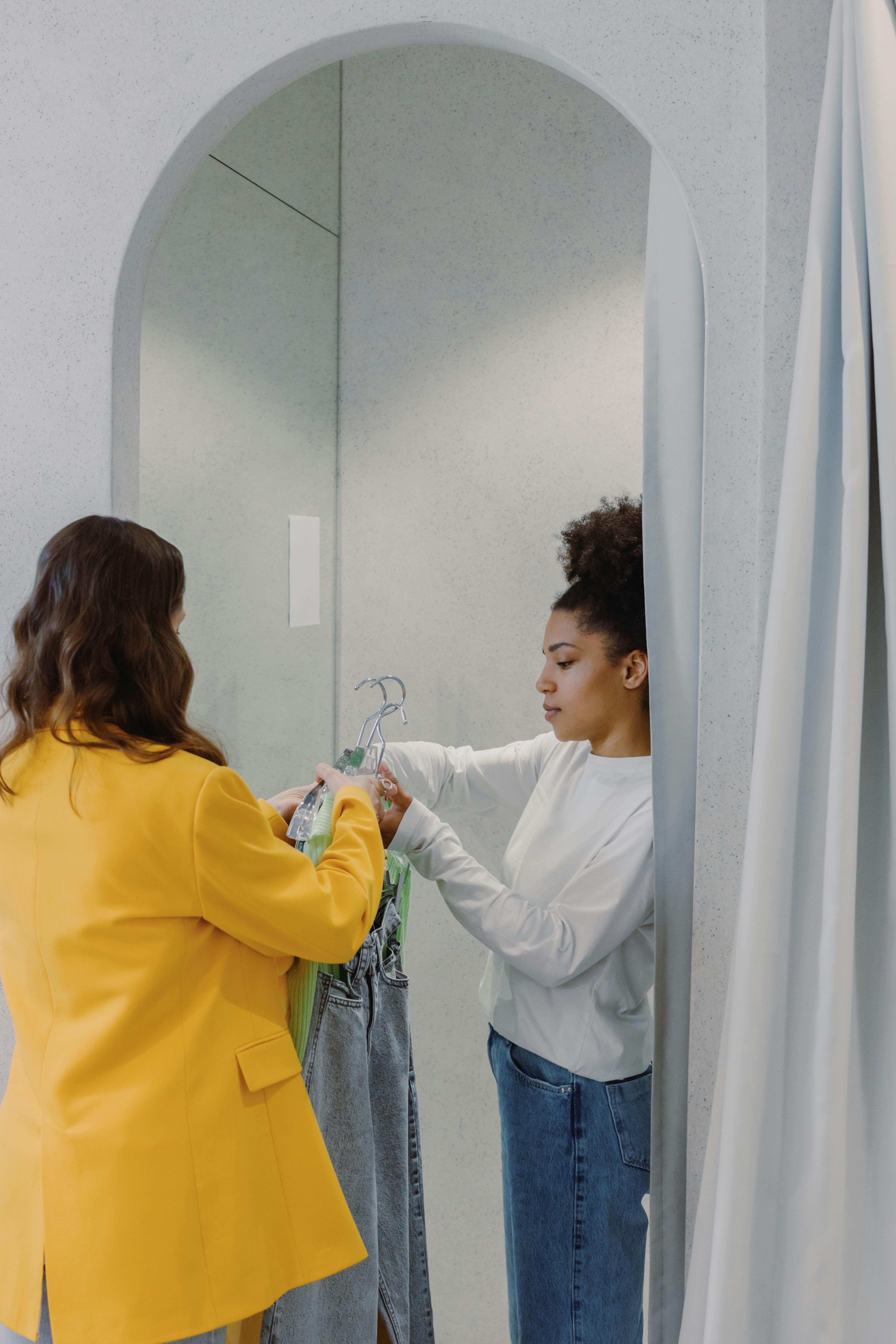 Two women in a fitting room discussing clothing choices together.